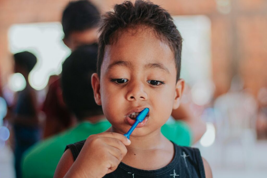 Parent helping child brush teeth